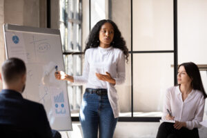 Woman stands at front of room presenting